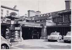 an old black and white photo of cars parked in front of a building on the street