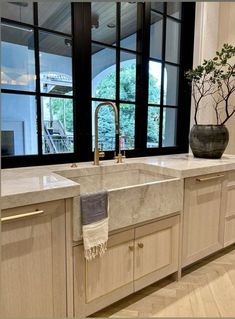 a kitchen with marble counter tops and wooden cabinets, along with a large window that looks out onto the outdoors