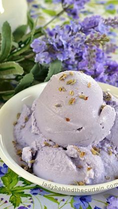 a bowl filled with ice cream next to purple flowers