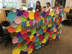 two women standing in front of a happy birthday sign made out of plates and letters