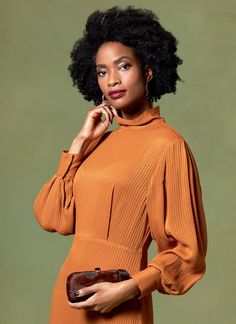 a woman in an orange dress is posing for the camera with her hand on her shoulder