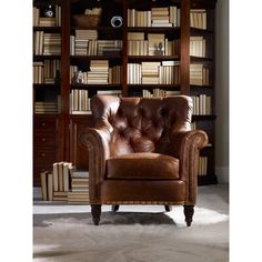 a brown leather chair sitting in front of a bookshelf