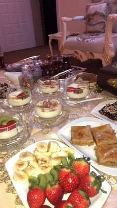 a table topped with lots of desserts and plates filled with fruit on top of it