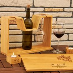 a wine bottle and two glasses on a wooden table with a brick wall in the background