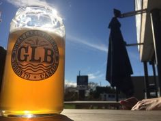 a close up of a beer glass on a table with a statue in the background