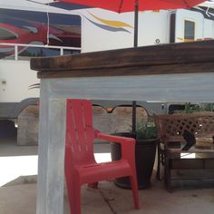 a red chair sitting under an umbrella next to a table with two chairs on it