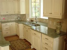 a kitchen with white cabinets and granite counter tops