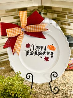 a white plate with a red bow on it that says happy thanksgiving sitting on a kitchen counter