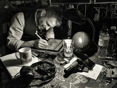 the man is writing on his desk next to an old photo