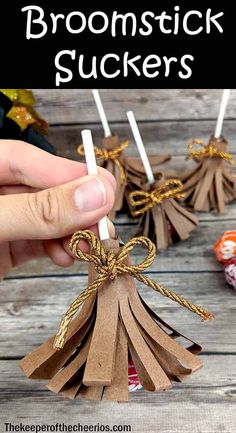 a hand holding some brown paper sticks with the words broomstick suckers on them