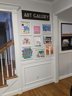 an art gallery is displayed on the wall next to a stair case with pictures and paintings