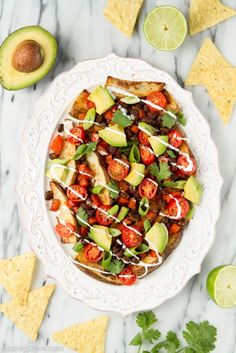 a white plate topped with an enchilada and tortilla chips on top of a marble table