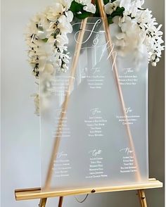 an easel holding a wedding program with flowers on it and the wording underneath