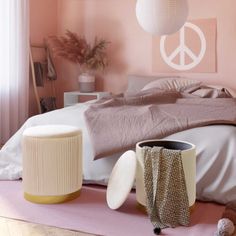 a bedroom with pink walls and white bedding, two vases on the floor