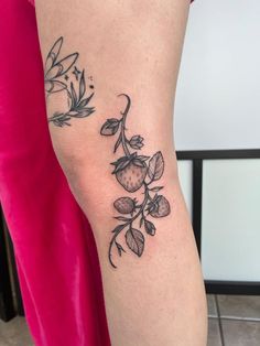 a woman's leg with a tattoo on it that has flowers and leaves growing out of it