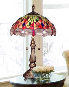 a table lamp sitting on top of a wooden table next to a vase filled with flowers