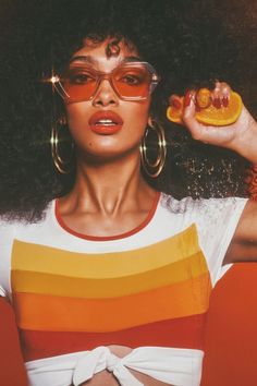 a woman with large hoop earrings holding an orange slice in front of her face and the words hot stuff on it