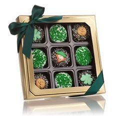 an open box of cupcakes with green frosting and shamrock decorations on them