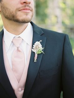 a man in a suit with a pink tie and boutonniere on his lapel