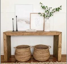 two baskets sitting on top of a wooden table next to a vase with flowers in it