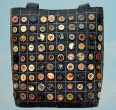 a handbag with buttons on it hanging from the ceiling in front of a blue wall