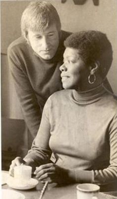 an old black and white photo of two people sitting at a table with coffee cups in front of them