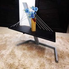 a vase with blue flowers in it sitting on a black table next to a mirror