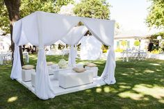 a white canopy bed sitting on top of a lush green field