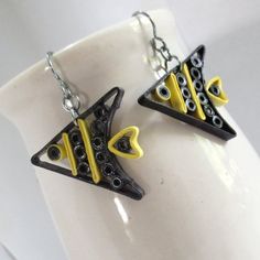 pair of black and yellow earrings sitting on top of a white vase next to each other