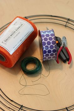 scissors, tape and other crafting supplies are on a circular wire tray with an orange piece of cloth