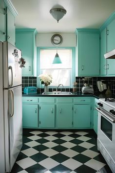 a kitchen with black and white checkered flooring, blue cabinets and green walls