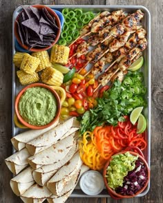 a platter filled with chicken, vegetables and tortillas