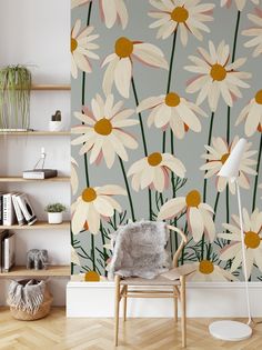 a chair sitting in front of a wall with daisies on it and bookshelves