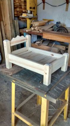 a wooden bed frame sitting on top of a table in a room filled with wood planks