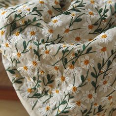 a white and yellow flowered fabric with green leaves on it's edges,