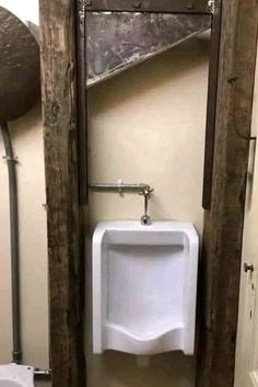 a white urinal sitting inside of a bathroom stall