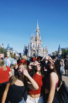 three girls standing in front of a castle with their hands on their faces and looking at the camera