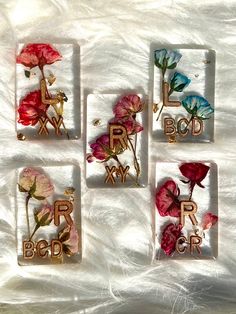 four glass coasters with flowers and letters on them