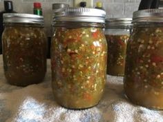 three jars filled with pickles sitting on top of a table