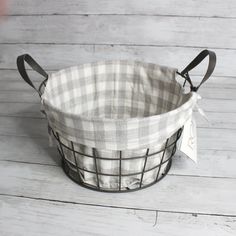 a black and white checkered basket sitting on top of a wooden floor next to a tag