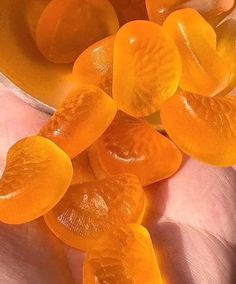 a person holding some orange pieces in their hand with the peels still on them