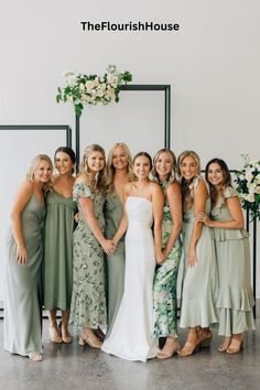 a group of women standing next to each other in front of a wall with flowers