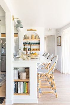 a kitchen with white walls and wooden flooring next to an open book shelf filled with books