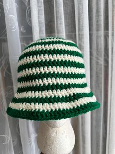 a green and white crocheted hat sitting on top of a mannequin head