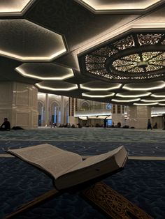 an open book sitting on top of a carpeted floor in a room with chandeliers