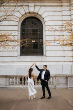 a man and woman dancing in front of a building