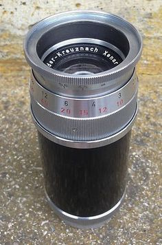 a camera lens sitting on top of a stone floor next to a cup with the lid open