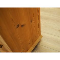 the corner of a wooden cabinet with wood flooring