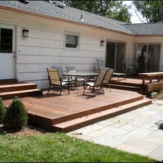 a deck with chairs and table in front of a house