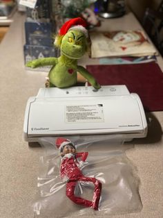 an elf doll sitting on top of a printer